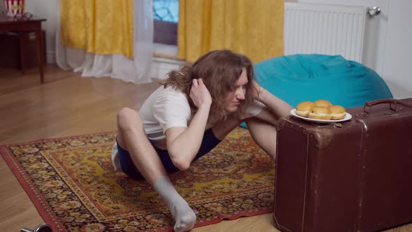 Wide Shot of Focused Motivated 70s or 80s Man Pumping Press at Home alt