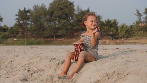Cute Little Child Girl Playing Drums on Sandy Beach