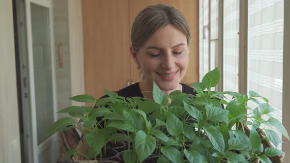 Smiling Middleaged Woman Examining Green Plants She Has Grown at Home