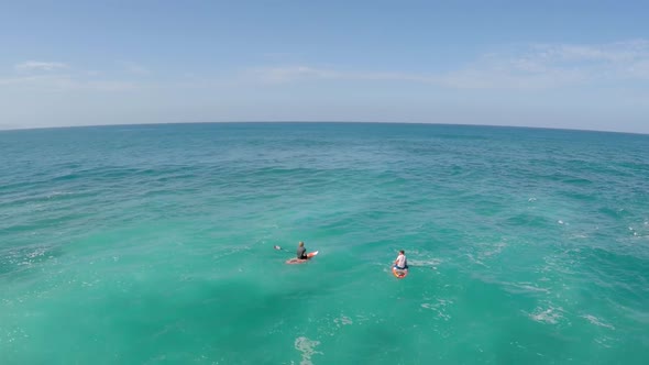 Aerial view of two men sitting on their boards while sup stand-up paddleboard surfing in Hawaii alt