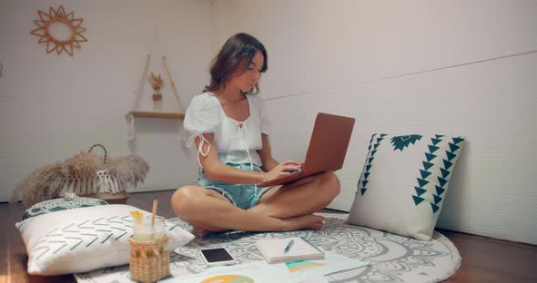 Woman Works From Home She Sits in Her House Room and Types on Keyboard of Her Laptop Computer alt