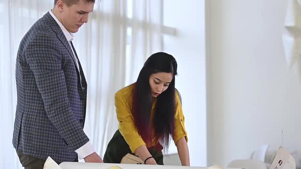 man and a woman work on drawings in the office alt