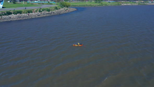 A man in a canoe fishing for food. Calm waters, Aerial, slow movement, top view. River over capital alt