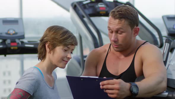 Fitness Trainer Talking to Woman in Gym alt