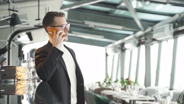 Portrait Of Serious Calm Man In Suit Talking On Phone While Standing In Restaurant