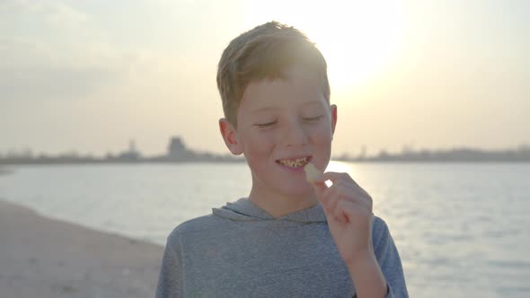 Boy Eating Cracker at Sunset. alt