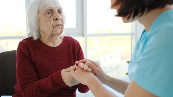 Aged Woman Talking to Nurse Holding Hands alt