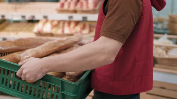 Male Supermarket Worker Displaying Fresh Bread alt