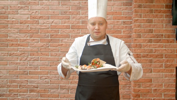 Friendly chef in uniform present a plate with seafood salad