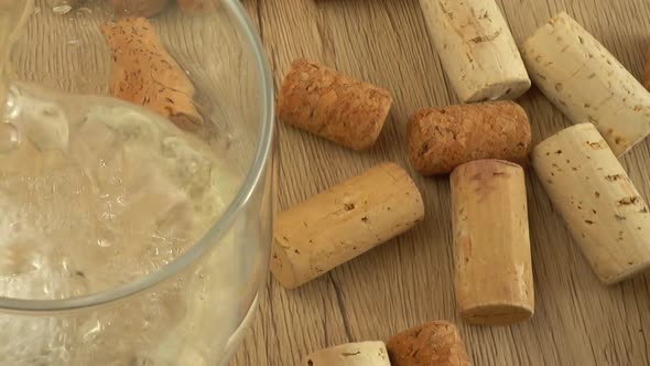 Wine is poured into a glass on the background of wine corks. alt