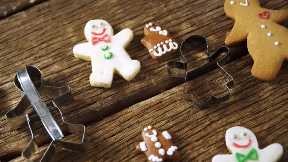 Cookie cutter and gingerbread cookies on wooden plank alt