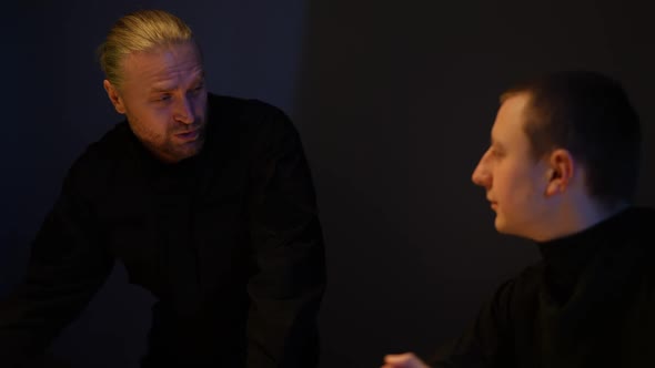 Portrait of Detective Explaining Suspicion Theory to Colleague in Darkness Indoors alt