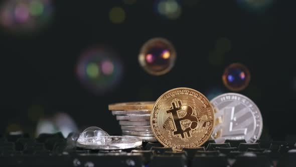 Cryptocurrency Bitcoin and Litecoin on a Black Background with Flying Soap Bubbles alt