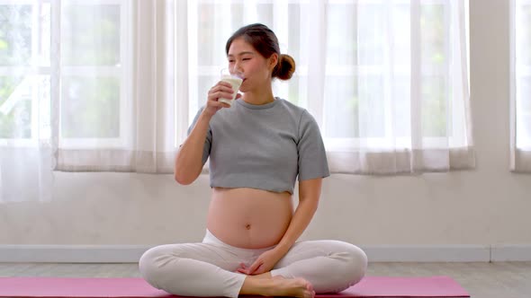 Pregnant Asian woman drinking fresh milk good source of calcium and protein for baby alt
