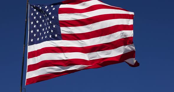 Slow Motion Real American Flag Waving In Wind Against a Deep Blue Sky