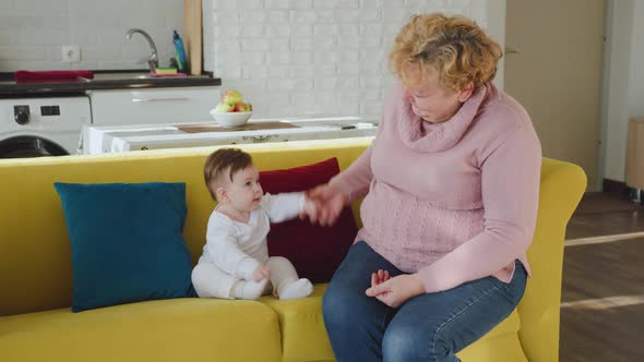 Happy Caucasian Grandmother Playing and Holding Her Little Granddaughter at Home alt