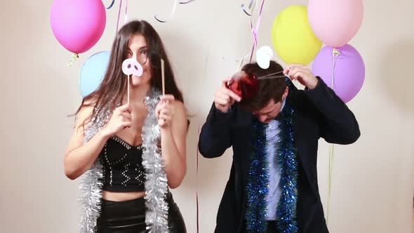Funny couple playing with props in photo booth alt