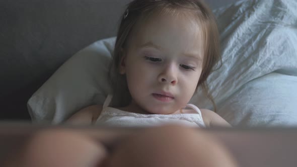 Cute Baby Watching Cartoon Using Tablet. Little Daughter Plays Games on a Smartphone. Learn alt