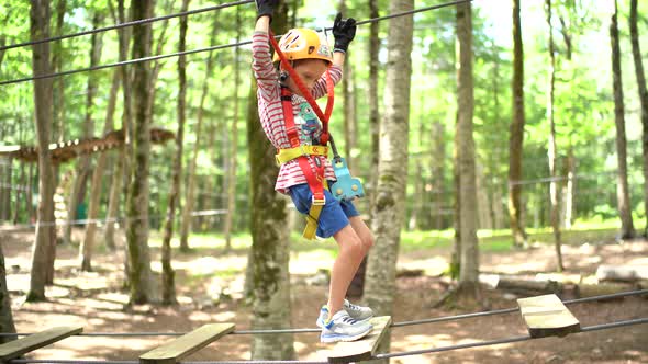Boy Walks Along an Agility Bridge with a Safety Rope alt