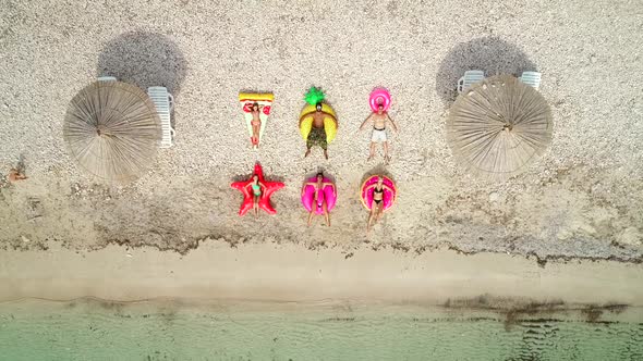 Aerial view of people lying on big inflatable mattresses on beach. alt