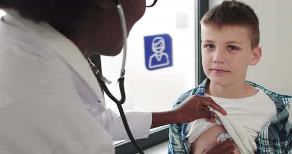 Young Black African Woman In A White Coat Pediatrician Examines A Sick Boy alt