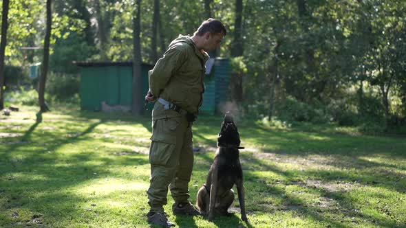 Wide Shot Dog Barking in Slow Motion with Professional Male Cynologist Spitting Looking at Camera alt