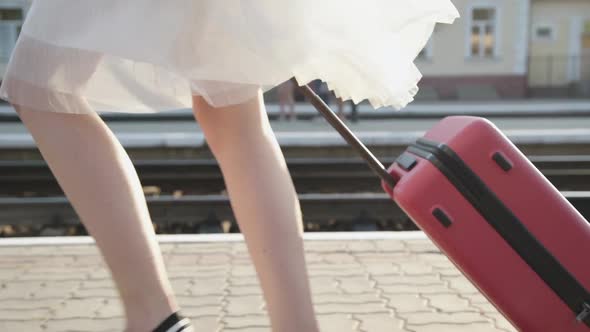 View of Girl's Stepping with Suitcase on Platform with Smile on Face alt