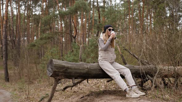 Wide To Close Up Shot Young Beautiful Blonde Woman in Waistcoat and Sunglasses Sitting on Log on 