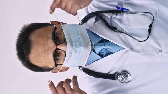 Vertical Shot Middle Aged Caucasian Doctor Puts on a Protective Sterile Medical Mask