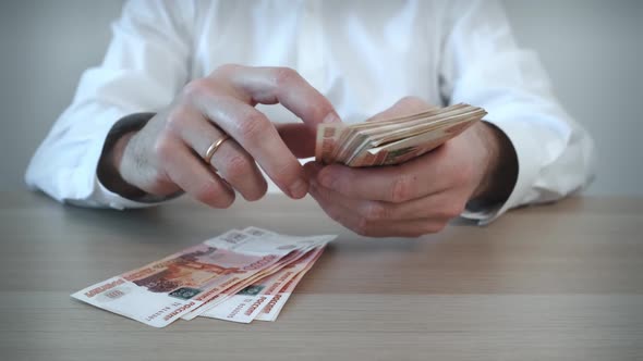 A Man Counts Out a Bundle of Five Thousand Russian Ruble Banknotes