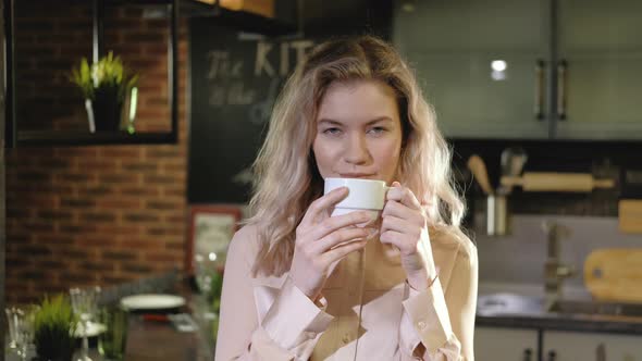 Portrait of beautiful successful woman drinking coffee in the evening in kitchen alt