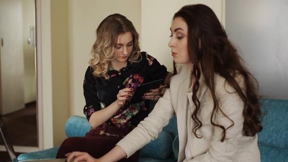 Two Beautiful Girls On The Couch With A Laptop And A Tablet Stock Footage