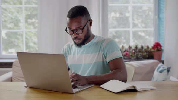 AfricanAmerican Ethnicity Man in Glasses Typing on Laptop at Home alt