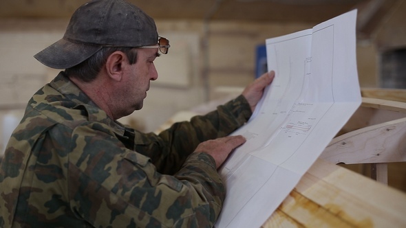 Carpenter Studies the Draft of the Boat at the Shipyard alt
