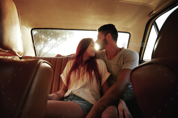 Affectionate young couple in rear seat of a car