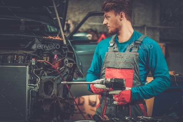 Mechanic with pneumatic tool in a workshop