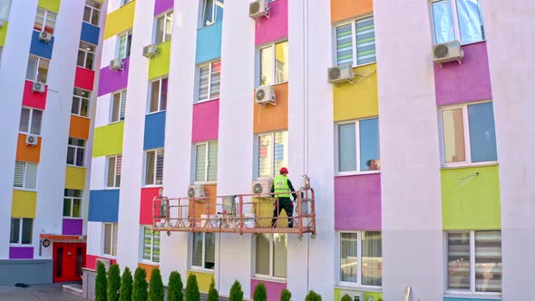 A Worker Paints The Facade Of A Building