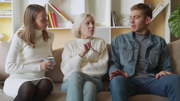 Elderly Mother and His Daughter Have a Warm and Friendly Conversation with Their Son at Home alt