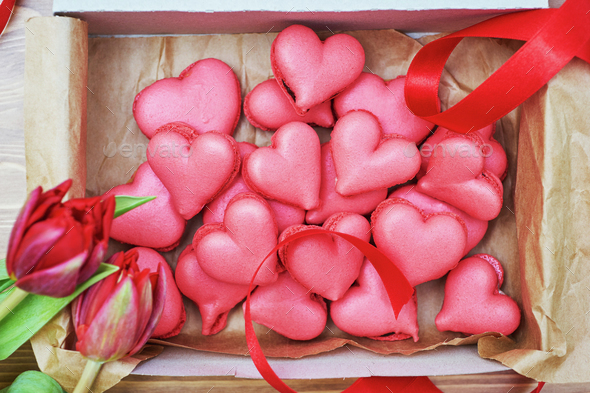 The box of heart-shaped macarons with flowers and ribbon on a wooden ...