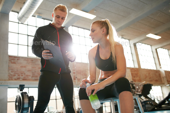 Personal trainer making an exercise plan for young woman - Stock Photo - Images