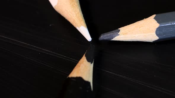 Macro shot of white, gray and black crayons forming a triangle, grayscale concept, close up view. alt