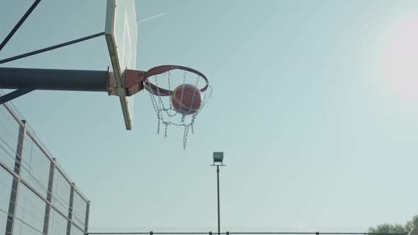 Basketball Ball Gets Into the Ring Against a Blue Sky Background