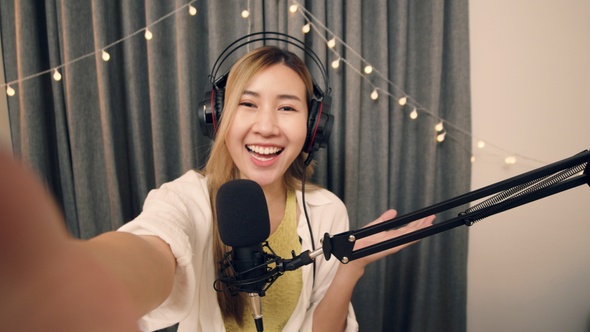 Asian influencer recording a vlog using podcast microphone.