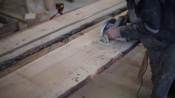 A Carpenter Saws Off a Board with a Disk Saw alt