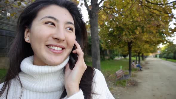 Slow Motion Close Up Asian Smling Girl Wearing White Sweater Talking By Smartphone and Walking in