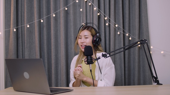 Asian woman influencer recording a vlog using podcast microphone for vlogging.