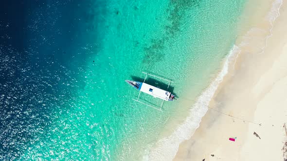Boat anchored on shore of tropical island with pristine sandy beach washed by clear emerald water of alt