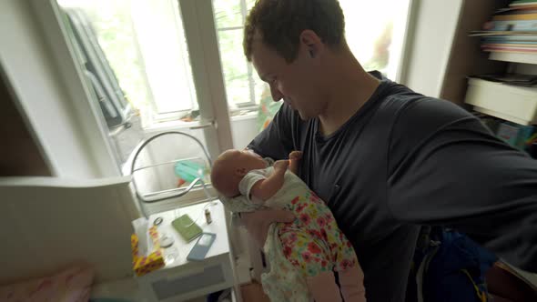 Dad lulling baby daughter at home alt