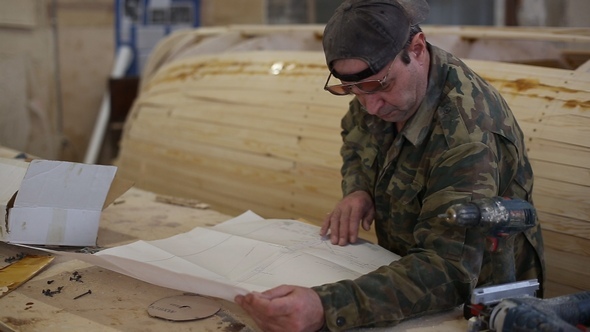 Carpenter Studies the Draft of the Boat at the Shipyard alt