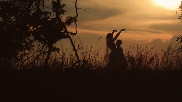 Silhouette Of Young Couple Dancing In The Field